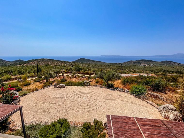 A stone spiral in the garden, hills and sea beyond