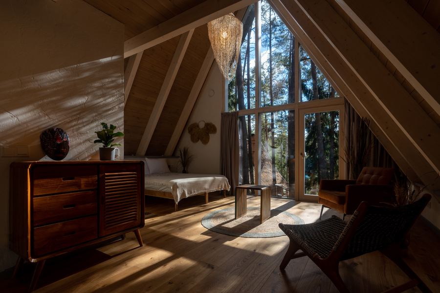 A bedroom under a pitched roof with a wall of windows