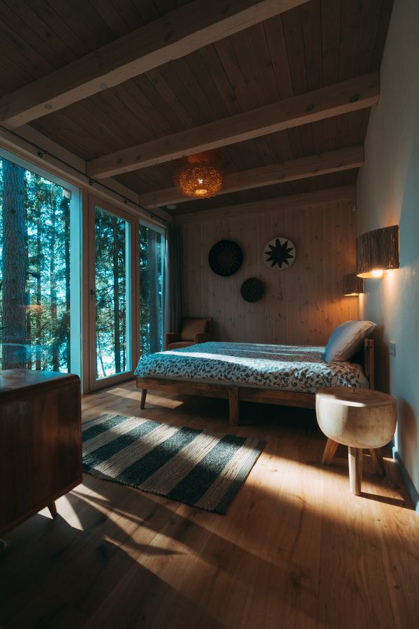 A bedroom with a window onto the pines