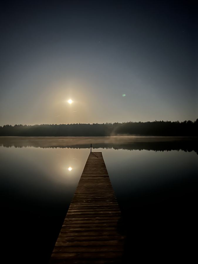 A wooden pier on the still lake at first light