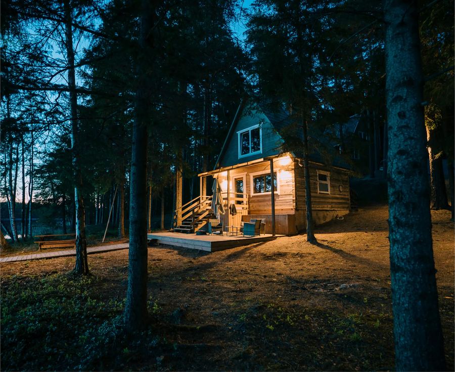 The sauna hut lit up at dusk among the trees